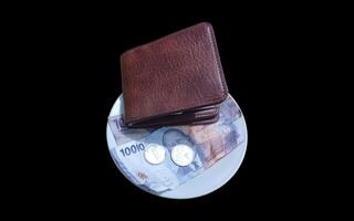 Ceramic cup with wallet and Indonesian rupiah banknotes on brown background. photo