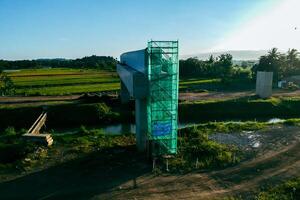 Sleman, Yogyakarta, Indonesia, 2024 - Toll road construction project over the Mataram ditch. A toll bridge is being built over the water flow so as not to displace rice fields and settlements photo