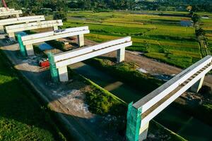 Sleman, Yogyakarta, Indonesia, 2024 - Toll road construction project over the Mataram ditch. A toll bridge is being built over the water flow so as not to displace rice fields and settlements photo