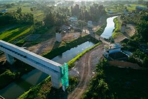 Sleman, Yogyakarta, Indonesia, 2024 - Toll road construction project over the Mataram ditch. A toll bridge is being built over the water flow so as not to displace rice fields and settlements photo