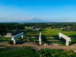 Sleman, Yogyakarta, Indonesia, 2024 - Toll road construction project over the Mataram ditch. A toll bridge is being built over the water flow so as not to displace rice fields and settlements photo