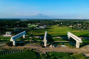 Sleman, Yogyakarta, Indonesia, 2024 - Toll road construction project over the Mataram ditch. A toll bridge is being built over the water flow so as not to displace rice fields and settlements photo