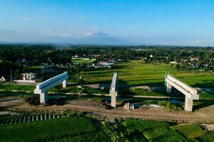 Sleman, Yogyakarta, Indonesia, 2024 - Toll road construction project over the Mataram ditch. A toll bridge is being built over the water flow so as not to displace rice fields and settlements photo