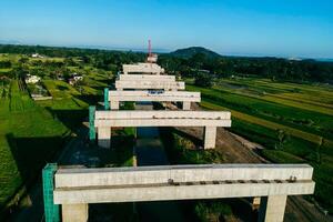 Sleman, Yogyakarta, Indonesia, 2024 - Toll road construction project over the Mataram ditch. A toll bridge is being built over the water flow so as not to displace rice fields and settlements photo