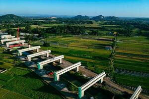 Sleman, Yogyakarta, Indonesia, 2024 - Toll road construction project over the Mataram ditch. A toll bridge is being built over the water flow so as not to displace rice fields and settlements photo
