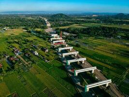 Sleman, Yogyakarta, Indonesia, 2024 - Toll road construction project over the Mataram ditch. A toll bridge is being built over the water flow so as not to displace rice fields and settlements photo