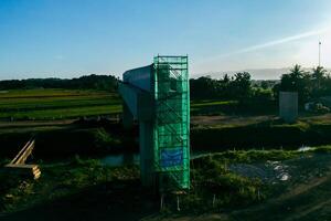 Sleman, Yogyakarta, Indonesia, 2024 - Toll road construction project over the Mataram ditch. A toll bridge is being built over the water flow so as not to displace rice fields and settlements photo