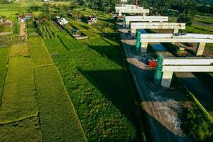 Sleman, Yogyakarta, Indonesia, 2024 - Toll road construction project over the Mataram ditch. A toll bridge is being built over the water flow so as not to displace rice fields and settlements photo