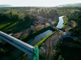 Sleman, Yogyakarta, Indonesia, 2024 - Toll road construction project over the Mataram ditch. A toll bridge is being built over the water flow so as not to displace rice fields and settlements photo
