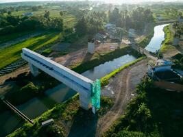 Sleman, Yogyakarta, Indonesia, 2024 - Toll road construction project over the Mataram ditch. A toll bridge is being built over the water flow so as not to displace rice fields and settlements photo