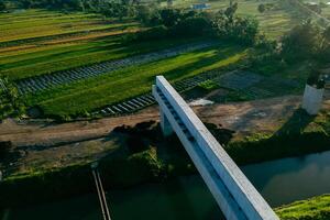 Sleman, Yogyakarta, Indonesia, 2024 - Toll road construction project over the Mataram ditch. A toll bridge is being built over the water flow so as not to displace rice fields and settlements photo