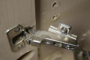 Torn-out hinge of furniture fittings. hinge fixed on a modern cabinet. Breakage of furniture fittings. Screw holes photo