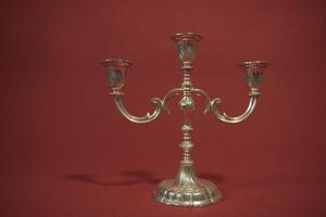 Decorative old candlestick with traces of time, before renovation. On a red background photo