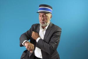 The train conductor looks at his wristwatch. Portrait of a train controller on a blue background. photo