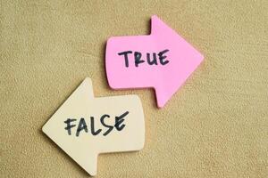 Concept of False or True write on sticky notes isolated on Wooden Table. photo