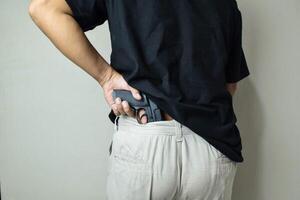 Man taking gun from waist photo