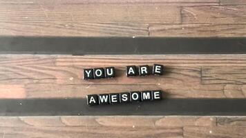 Concept of You Are Awesome written on wooden blocks. Cross processed image on Wooden Background photo