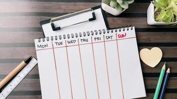 Concept of Weekly Calendar write on book isolated on Wooden Table. photo