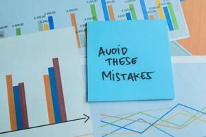 Concept of Avoid These Mistakes write on sticky notes isolated on Wooden Table. photo