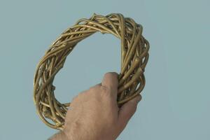 A wreath of dry branches in a man's hand in motion. Close-up on a blue background photo