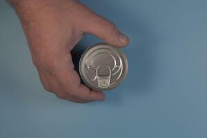 A tin can in the man's hand. Flatlay on a blue background close-up photo