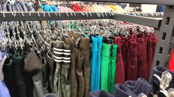 Row of different colorful pants trousers on hanger in shop, photo