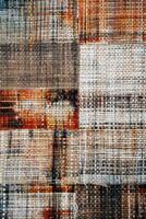 Vertical background of woven fabric with intertwined threads in various warm colors photo