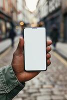 A person holding a smartphone with a blank screen in a city street. photo