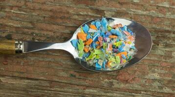Microplastics in a spoon. A concept of consuming micro plastic particles, water and soil pollution. photo