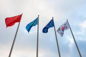 View of the flags of China, Kazakhstan, South Korea and Commonwealth of Independent States on the background of cloudy sky photo