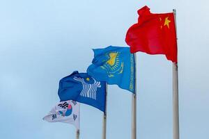 View of the flags of China, Kazakhstan, South Korea and Commonwealth of Independent States on the background of cloudy sky photo
