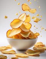 Slight yellow color cassava chips falling into a bowl on white background, food photo studio concept with white background