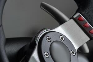 Close up view on a racing steering wheel with red buttons and metal gearshift paddles photo