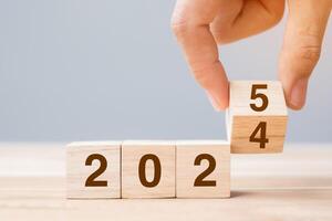hand flip cube block 2024 to 2025 text on table. Resolution, review, strategy, end year, goal, business and New Year holiday concepts photo