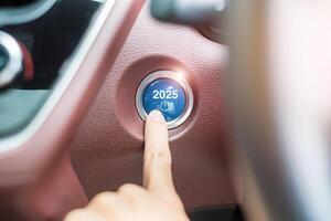 Finger press a car ignition button with 2025 START text inside automobile. New Year New You, forecast, resolution, motivation, change, goal, vision, innovation and planning concept photo
