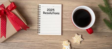 2025 Resolutions with notebook, black coffee cup, Christmas cookies and pen on wood table, Top view and copy space. Xmas, Happy New Year, Goals, To do list, Strategy and Plan concept photo