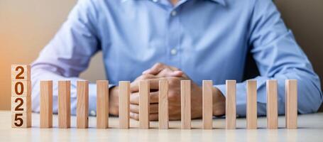 Businessman with 2025 wooden Blocks. Business, Risk Management, Insurance, Resolution, strategy, solution, goal, New Year New You and happy holiday concepts photo
