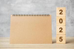 2025 Happy New Year with blank notebook and wooden number. countdown, Resolution, Goals, Plan, Action and Mission Concept photo