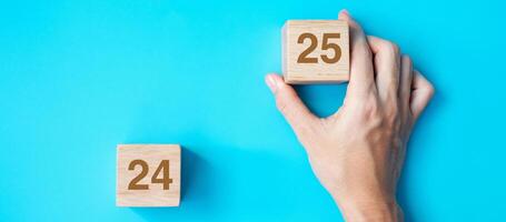 hand holding wooden cube block with 2025 text on blue background. Resolution, plan, review, goal, start and New Year holiday concepts photo