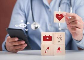 Hand of doctor arranging wood blocks with healthcare medical icons and using smartphone with conversation icons. Space for text. Health and medical concept photo