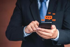 Businessman using a smartphone with conversation icons while standing in the studio with a vintage background. Close-up photo. Space for text. Communication and technology concept photo