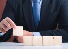 Hand of businessman arranging empty wooden blocks. Close-up photo. Space for text. Business and strategy planning concept photo