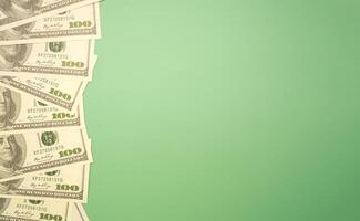 Top view of one hundred dollar banknotes laid isolated green background. Flat lay. Space for text. USD currency, business, and finance concept photo