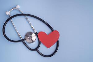 A stethoscope and red paper a heart shape isolated on a light blue background. Close-up photo. Top view. Flat lay with Space for text. Healthcare and medicine concept photo