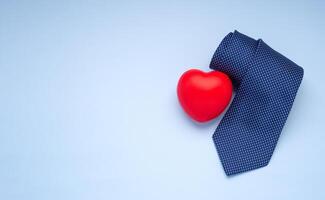 Happy Father's Day with a blue tie and red heart laid isolated on a light blue background with space for text. Top view. Flat lay photo