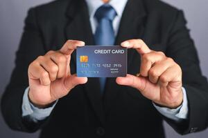 Businessman holding a mockup blue credit card while standing in a studio with copy space for text. Close-up photo. Money and business concept photo