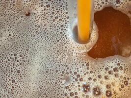 Close-up of craft beer and foam in a fermentation container. Process of making home beer from malt. Craft beer from barley and dark malt photo