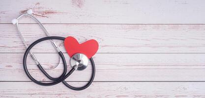 A stethoscope and red paper a heart shape on a wooden background. Close-up photo. Top view. Flat lay with Space for text. Healthcare and medicine concept photo