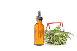 A bottle of cannabis oil extracts and green marijuana leaves in a mini basket isolated on a white background. Medical cannabis plantation and business concept photo