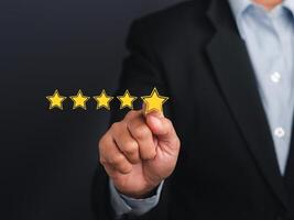 Businessman pointing five-star symbol to increase the rating of the business against a gray background. Customer feedback and experience concept photo